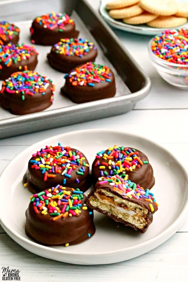 plate of gluten-free no-bake cracker cookies with a pan of cookies and bowl of sprinkles in the background