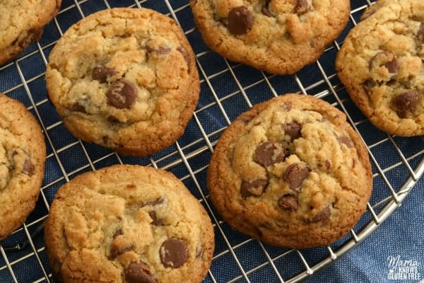 gluten-free chocolate chip cookies on a silver cooling rack with a blue kitchen underneath