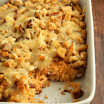 Gluten-free Reuben casserole baked in a white baking dish with melted Swiss cheese and toasted bread cubes on top.