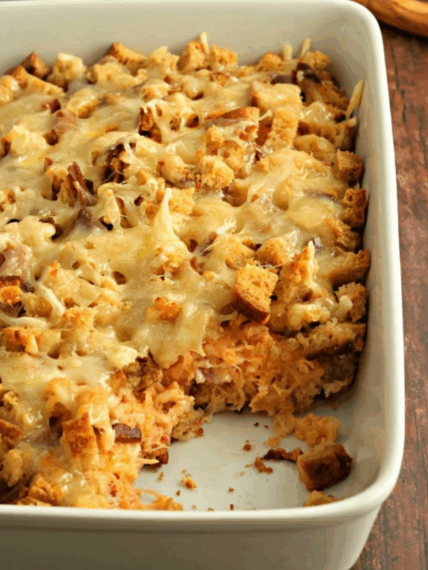 Gluten-free Reuben casserole baked in a white baking dish with melted Swiss cheese and toasted bread cubes on top.