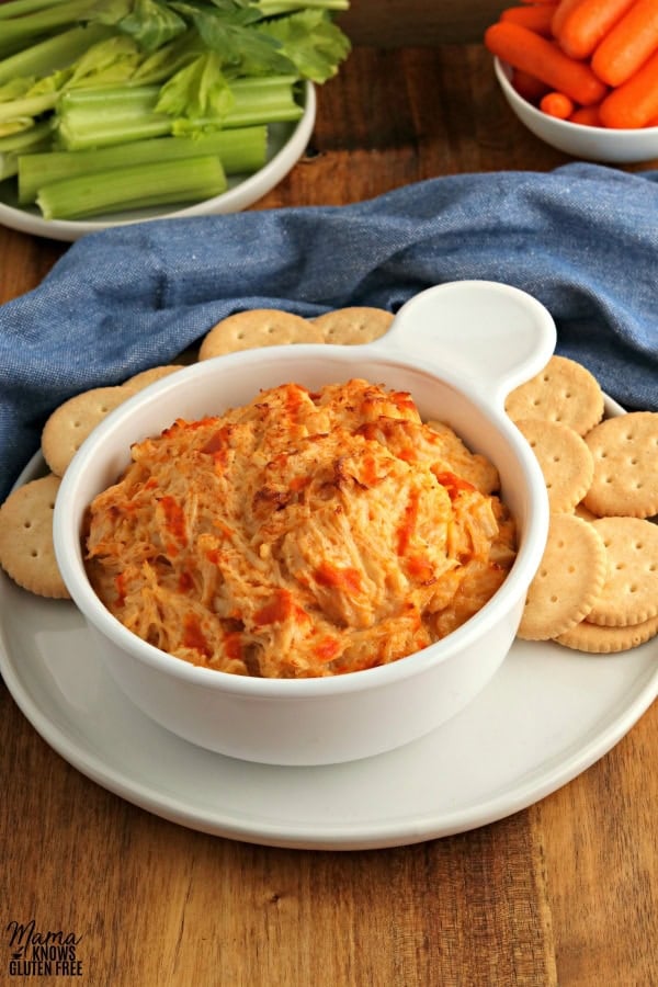 bowl of buffalo chicken dip with crackers and celery and carrots in the background