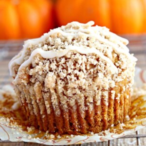 gluten-free pumpkin muffin with crumb topping and pumpkins behind it