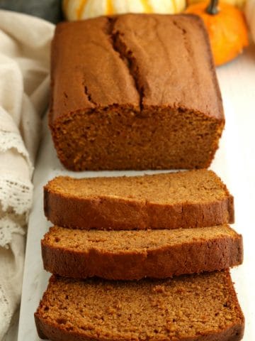 loaf of gluten-free pumpkin bread with 3 slices cut out of it