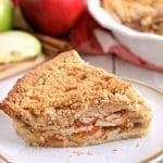 slice of gluten-free apple pie with the pie and apples in the background