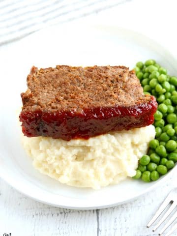 slice of gluten-free meatloaf with mashed potatoes and green peas