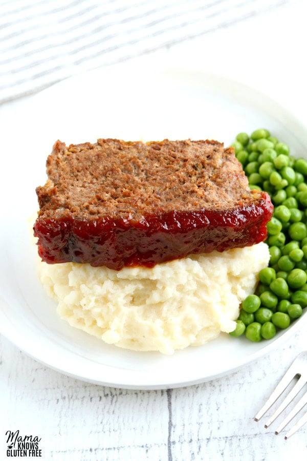 a slice of gluten-free meatloaf with mashed potatoes and green peas