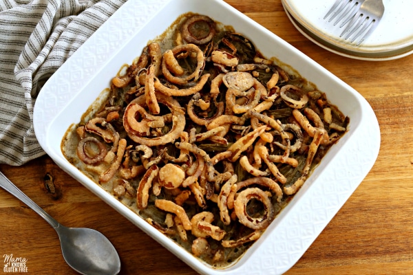 gluten-free green bean casserole with serving spoon, kitchen towel and plates in the background