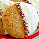 gluten-free gingerbread cookies with half dipped in white chocolate and sprinkles on a red plate