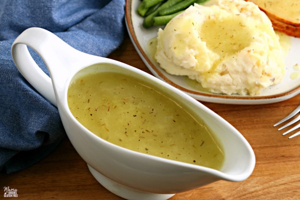 gravy boat filled with gluten-free gravy with a plate of mashed potatoes in th backgrounde