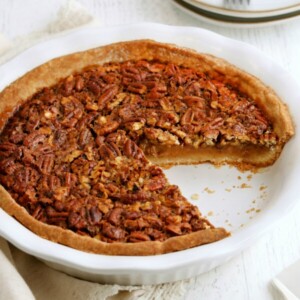 gluten-free pecan pie with a slice cut out of it with plates in the backgorund