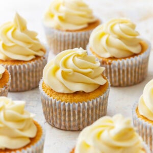 frosted gluten-free vanilla cupcakes in cupcake liners.