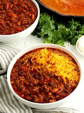 2 bowls of gluten-free chili with cornbread and clintro in the background