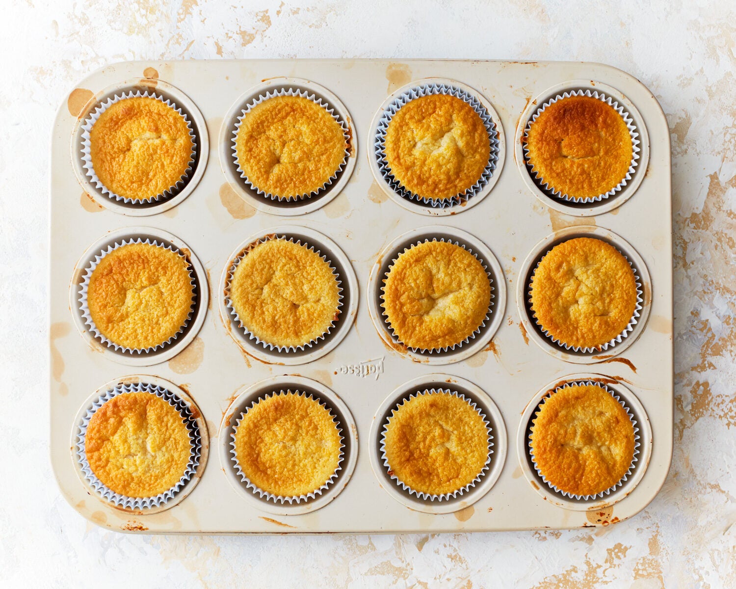 baked gluten-free vanilla cupcakes in a cupcake tin.