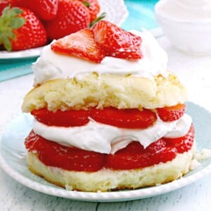 gluten-free strawberry shotcake on a blue plate with stawberries and whipped cream in the background