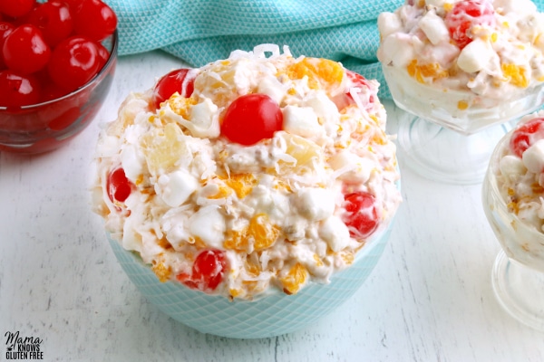 bowl of ambrosia salad with cherries in the background 
