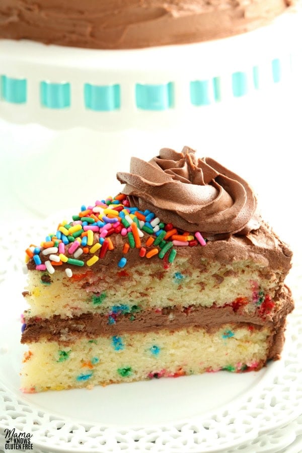 slice of gluten-free birthday cake on a white plate with the cake in the background