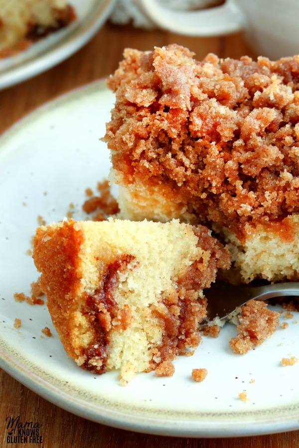 bite of gluten-free coffee cake on a forth with the cake in the background