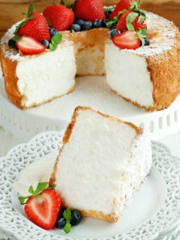 gluten-free angel food cake slice on a white plate with the cake in the background