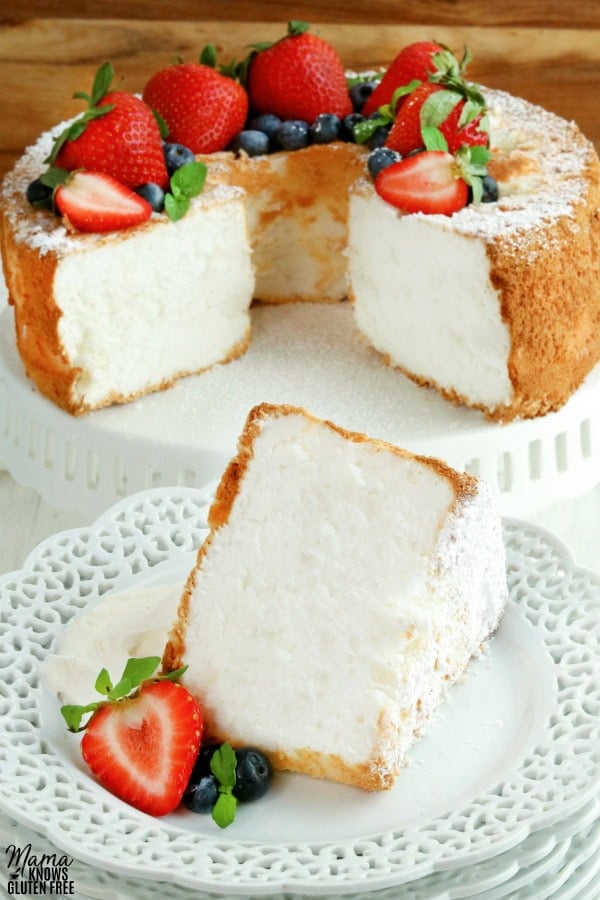 gluten-free angel food cake slice on a white plate with the cake in the background