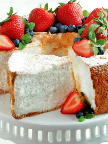 gluten-free angel food cake topped with berries on a white cake plate