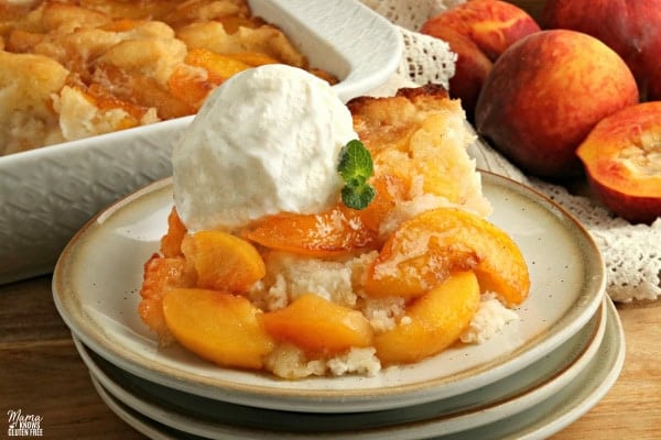 gluten-free peach cobbler with vanilla ice cream on a plate with the cobbler in the background