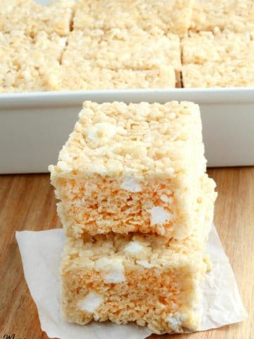 gluten-free rice krispies treats stacked on top of each other with the pan in the background