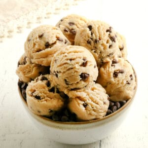 gluten-free cookie dough in a white bowl with a lace napkin in the background