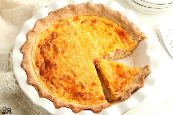 gluten-free quiche in white pie pan with slice cut