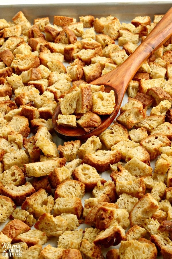 gluten-free crouotns on a baking sheet with a wooden spoon