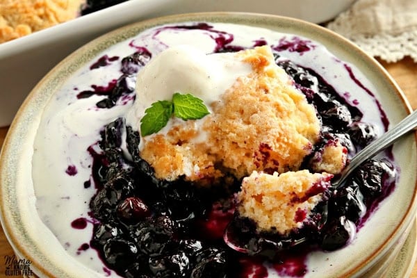 gluten-free bluberry cobbler serving with ice cream on a plate with a spoon