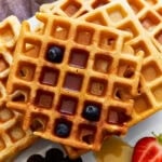 overhead view of a stack of gluten-free waffles with syrup and blueberries.