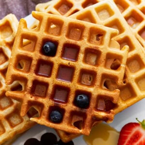 overhead view of a stack of gluten-free waffles with syrup and blueberries.