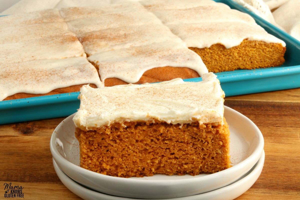 gluten-free pumpkin bar on a white plate with the pan of bars in the background.