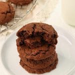 gluten-free chocolate cookies stacked ona white plate with cookies in teh background on a cooling rack