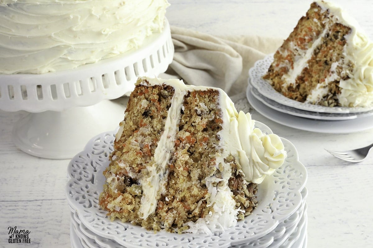 gluten-free carrot cake slice on a white plate with another slice and the cake in the background