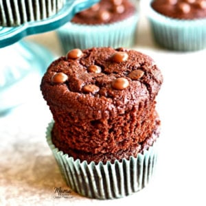 Two Paleo chocolate muffins stacked on top of each other with more muffins in the background