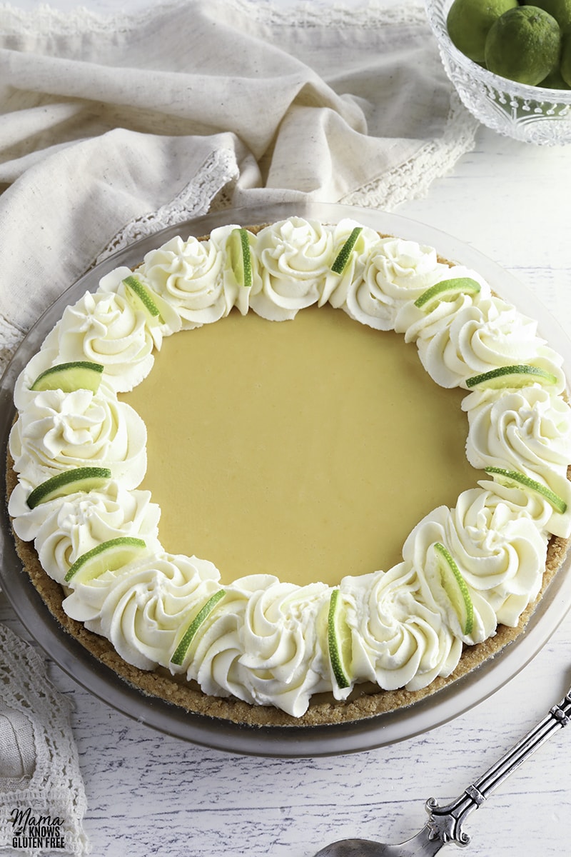 gluten-free key lime pie topped with whipped cream and lime slices