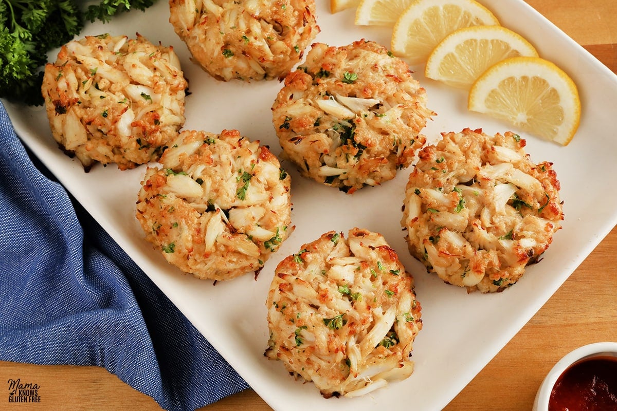 gluten-free crab cakes on a white platter with lemon slices and parsley