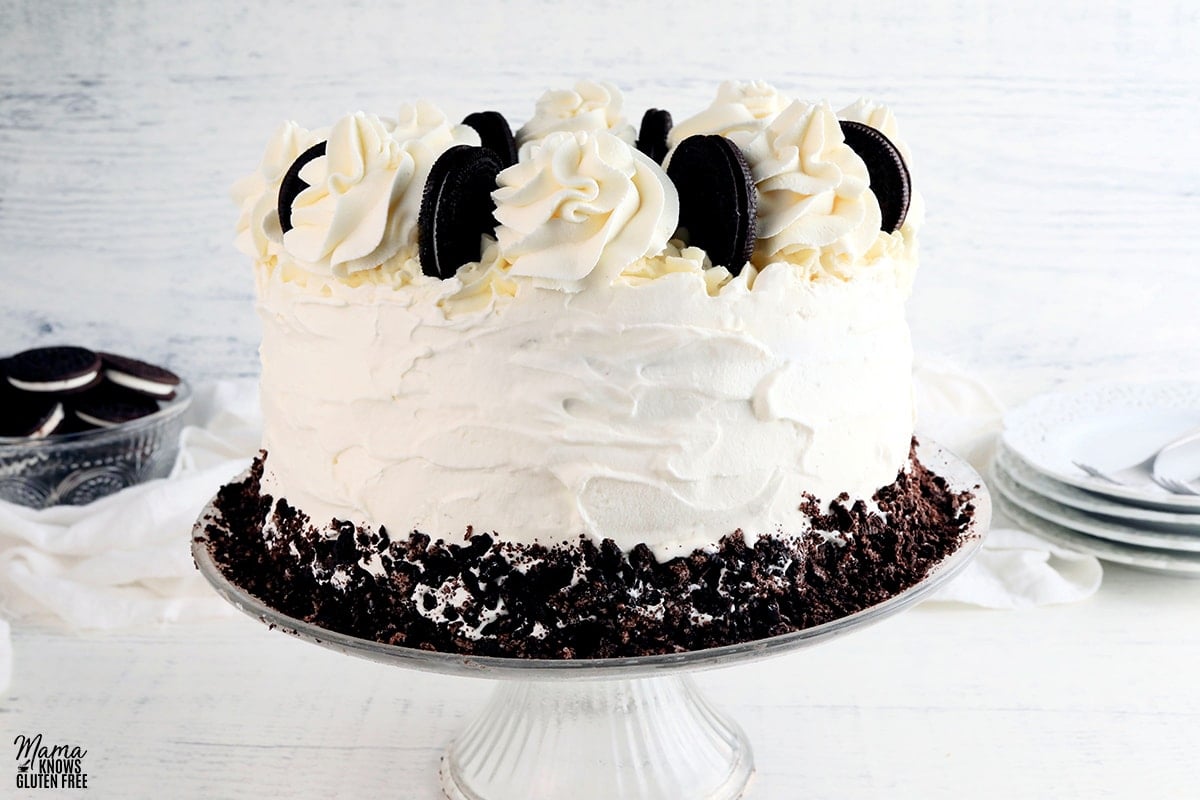 gluten-free ice cream cake on a cake plate with plates and bowl of cookies in the background