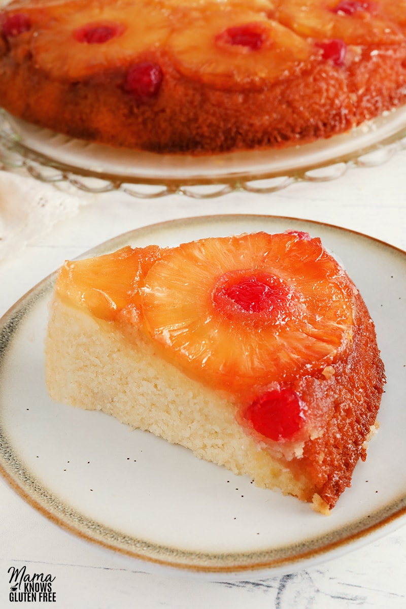 gluten-free pineapple upside down cake slice on a white plate with the cake in the background