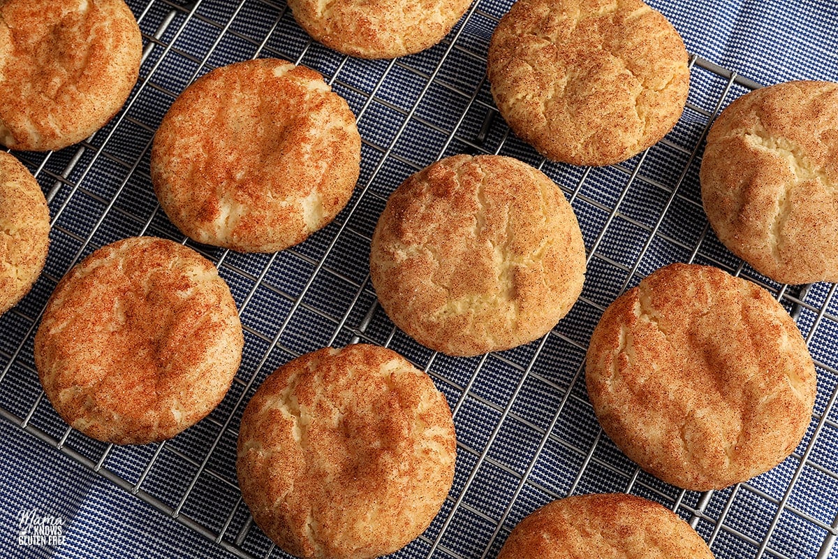 gluten-free snickerdoodle cookies on a cooling rack with a blue kitchen towel