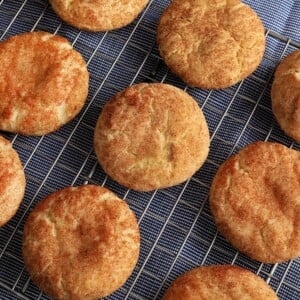 gluten-free snickerdoodle cookies on a sliver cooling rack on top of a blue kitchen towel