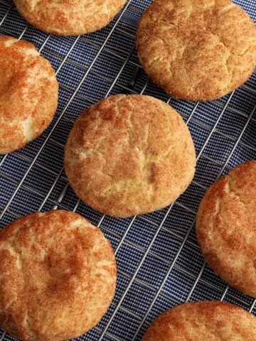 gluten-free snickerdoodle cookies on a sliver cooling rack on top of a blue kitchen towel