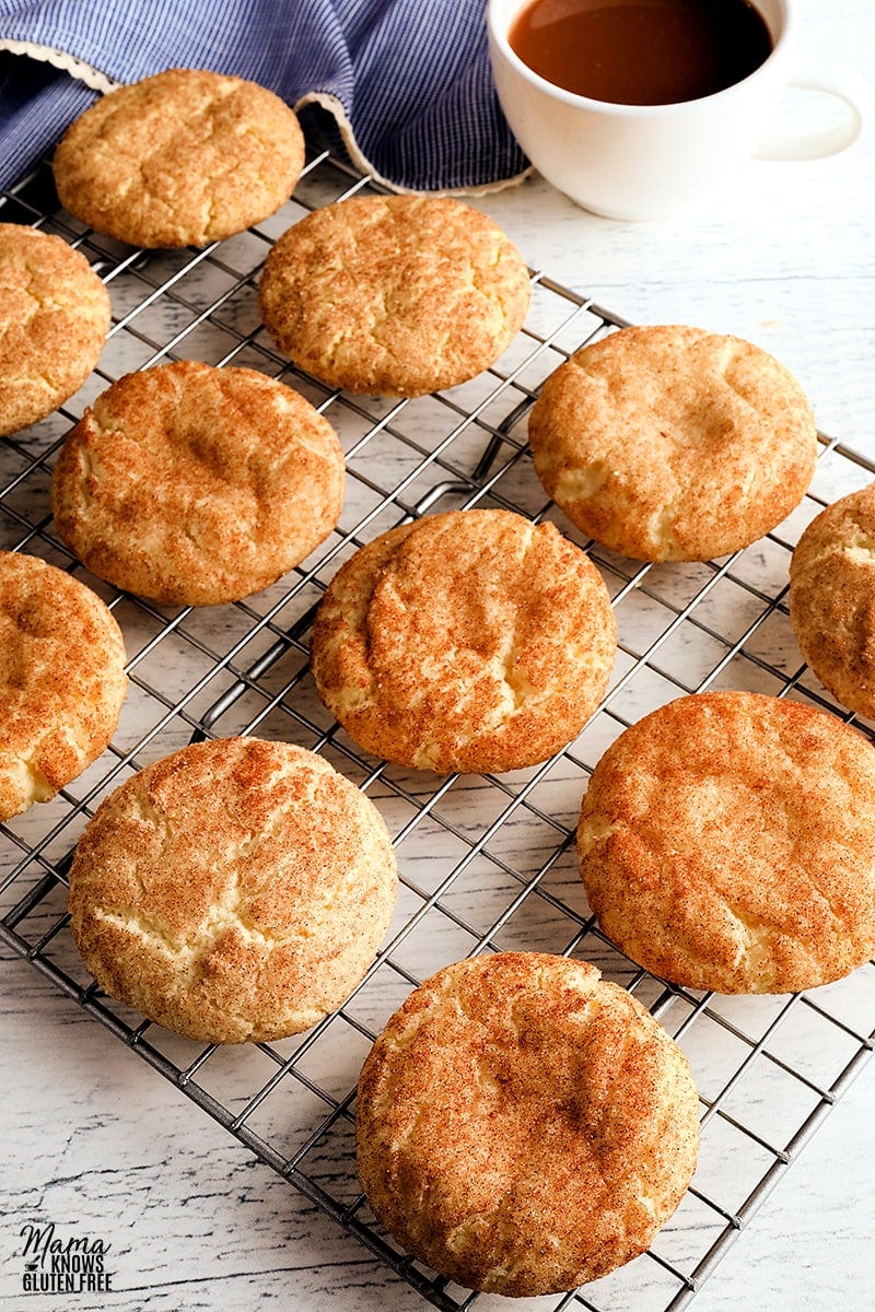 gluten-free snickerdoodle cookies on a cooling rack with a cup of coffee and blue napkin