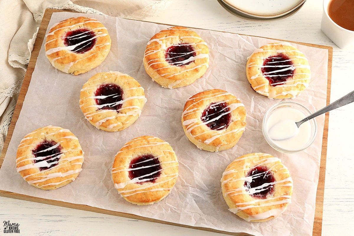 gluten-free Danish on parchment paper with a bowl of glaze and a spoon