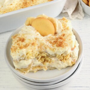 gluten-free banana pudding on a white plate with pan of pudding in the background