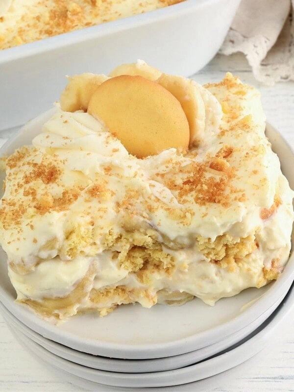 gluten-free banana pudding on a white plate with pan of pudding in the background