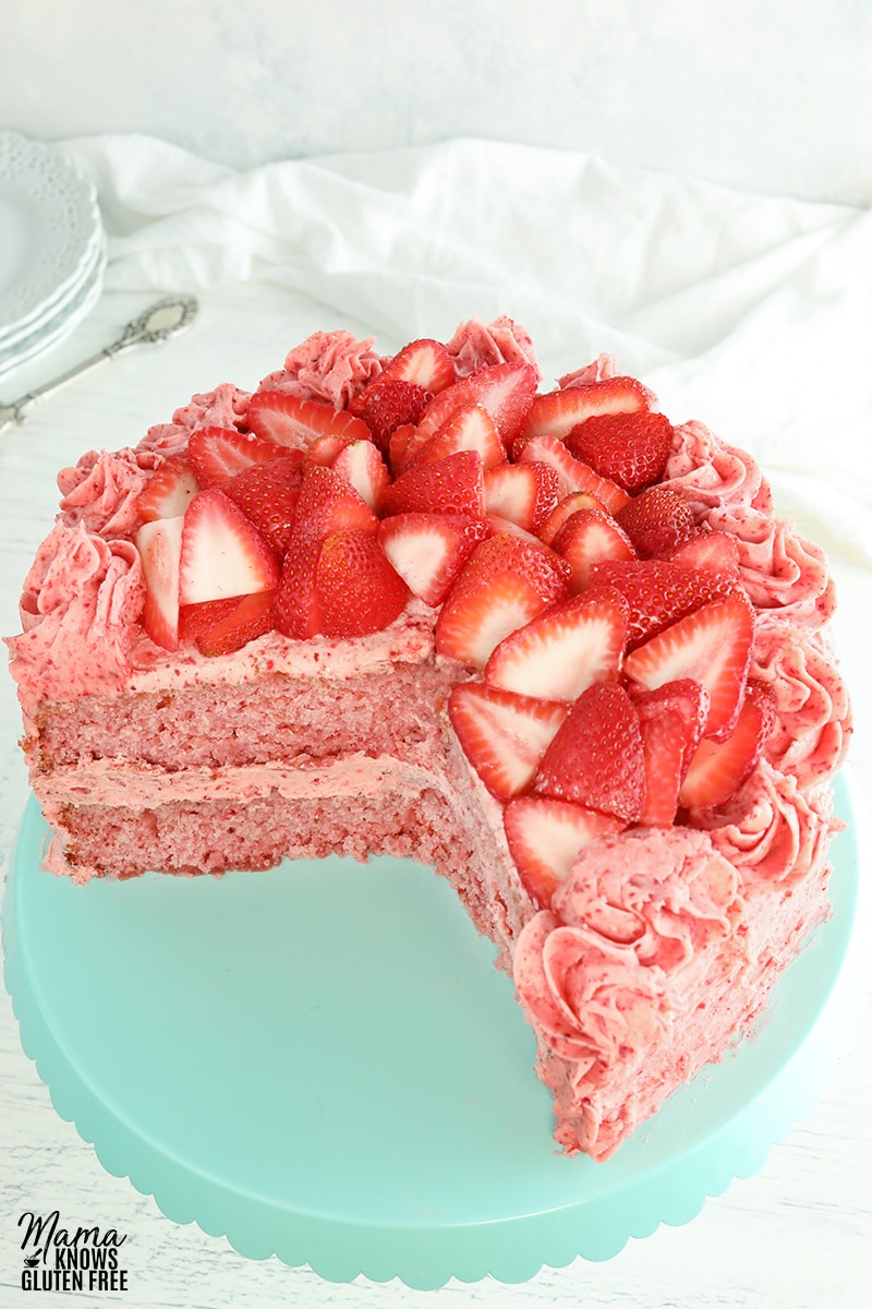 gluten-free strawberry cake on a blue cake plate with white plates and cake sever in the background