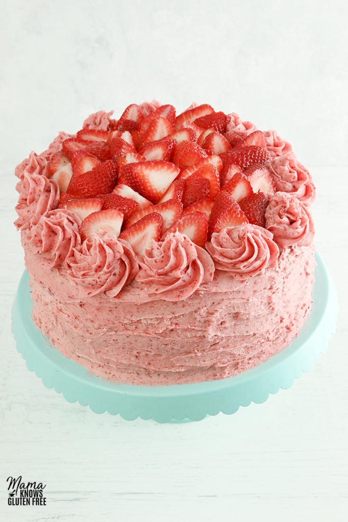 gluten-free strawberry cake on a blue cake stand with a white background