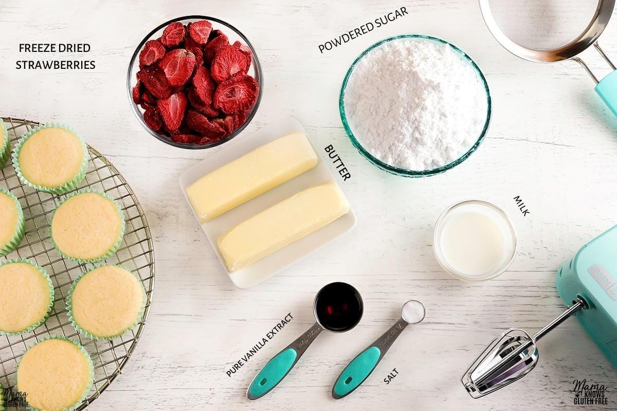 strawberry frosting ingredients and cupcakes on a cooling rack 